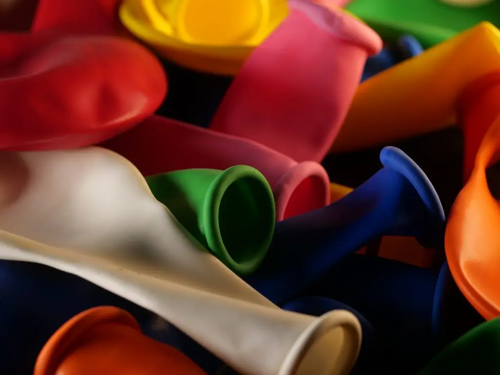 A close crop of uninflated balloons in red, pink, green, blue, orange and cream