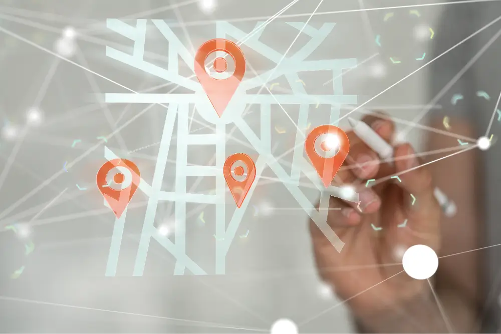 A hand draws on a translucent street map marked with orange location pins and linked by network lines