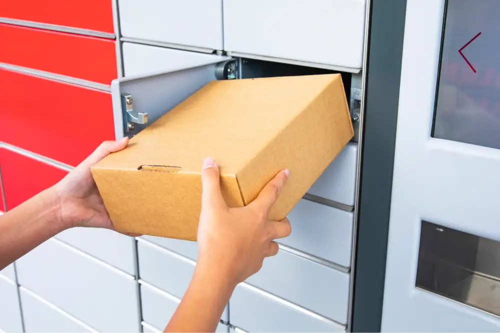 Hands taking a cardboard parcel from an open parcel locker