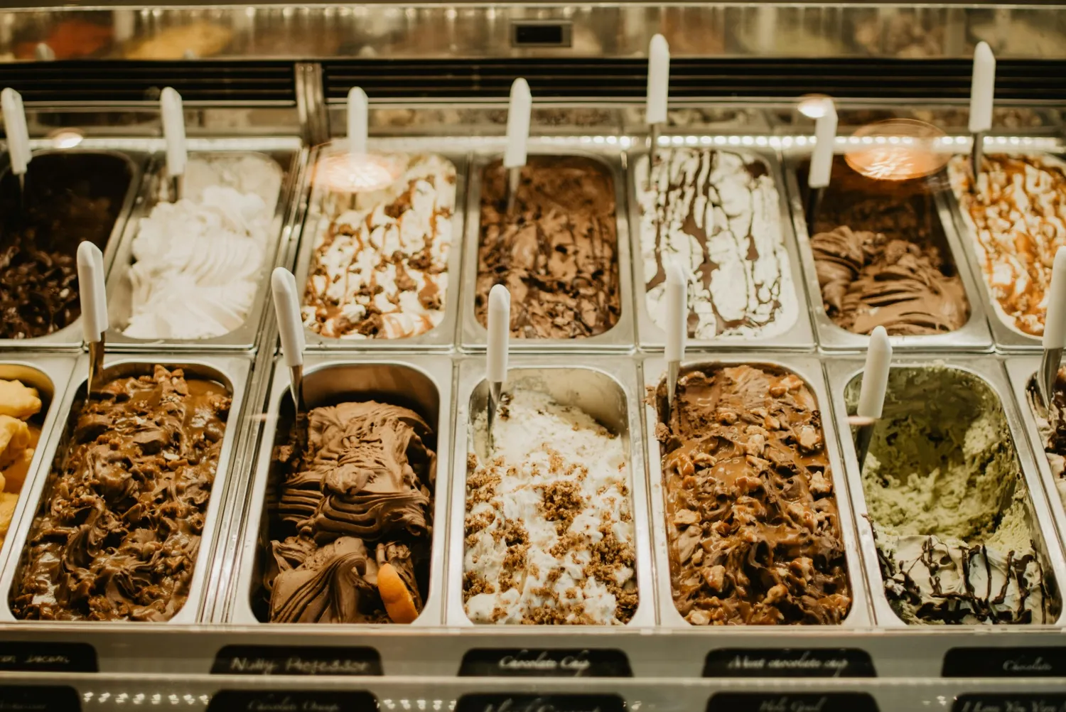 Trays of chocolate, caramel, pistachio and cookie ice cream flavours in a lit display freezer
