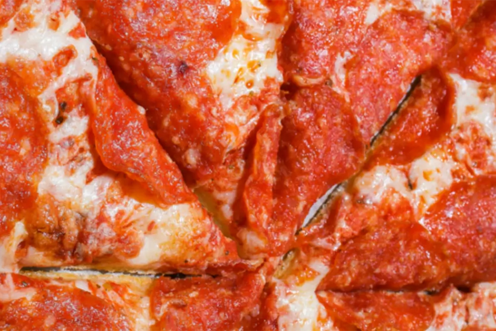 A close crop of a pepperoni pizza cut into slices
