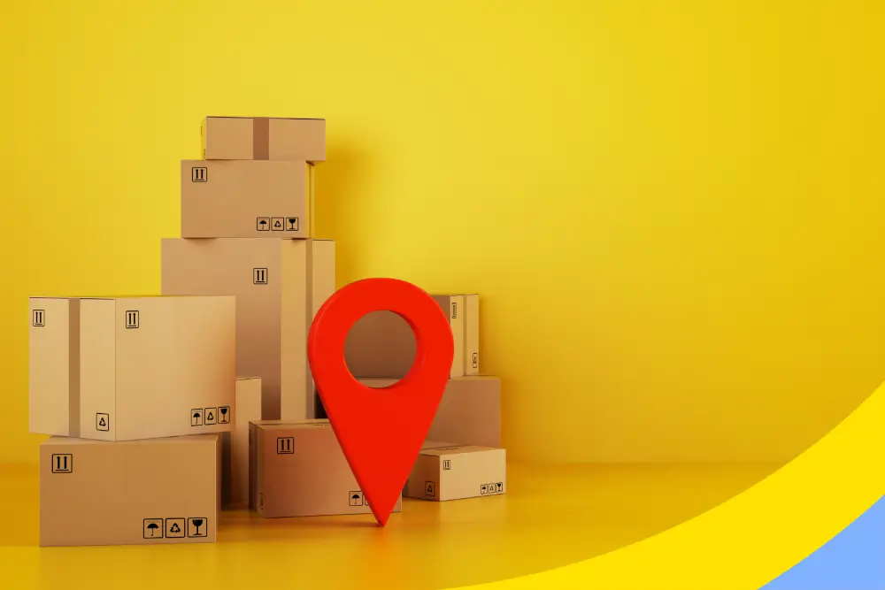 A large red location pin standing among stacked cardboard boxes on a yellow background