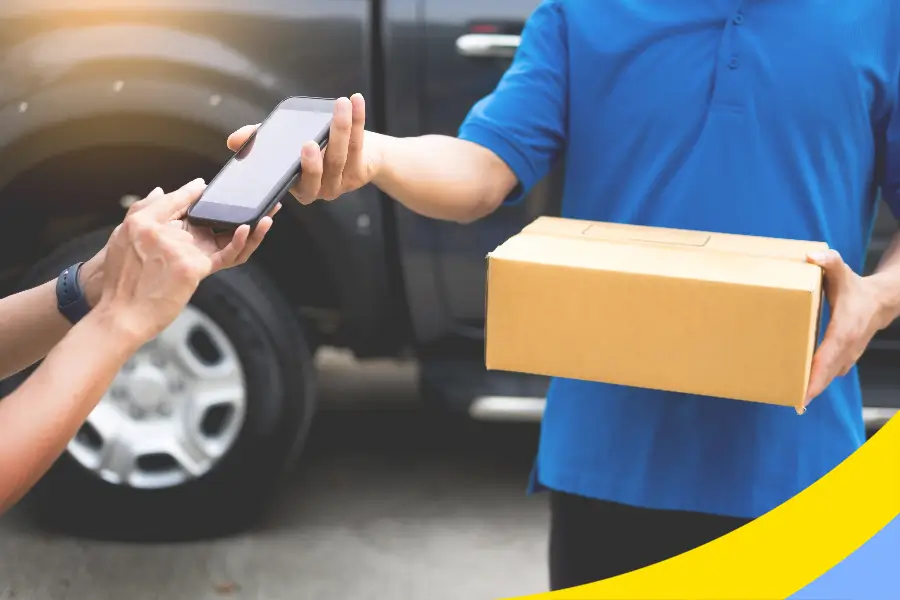 A courier handing over a carton while the customer signs on a phone screen