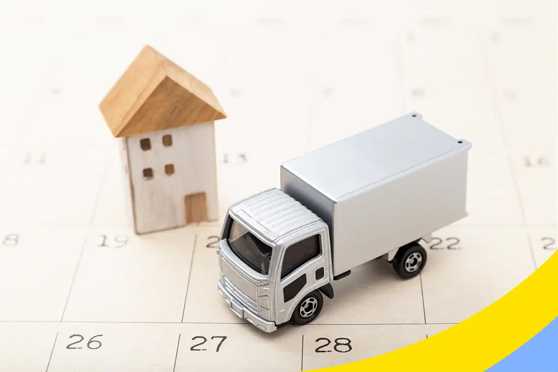 A toy box truck and a small wooden house standing on a paper calendar
